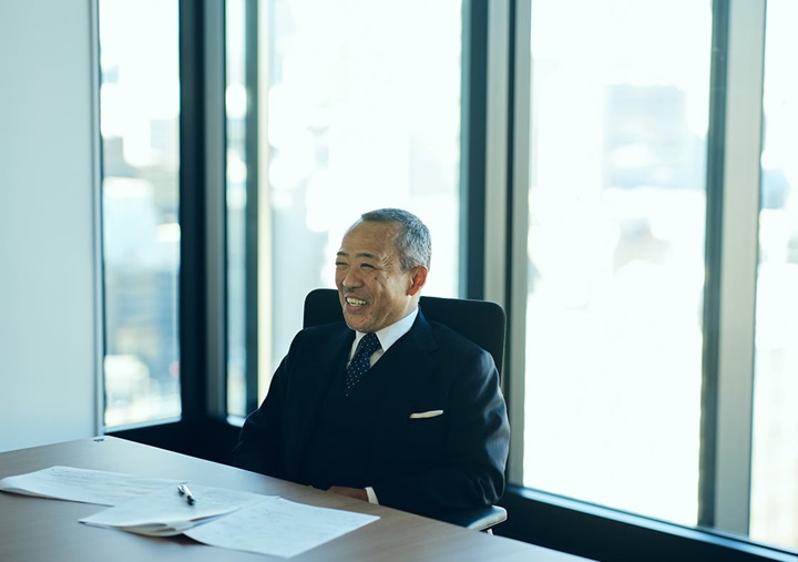 Tomohiro Sudo is sitting on a black chair and speaking.