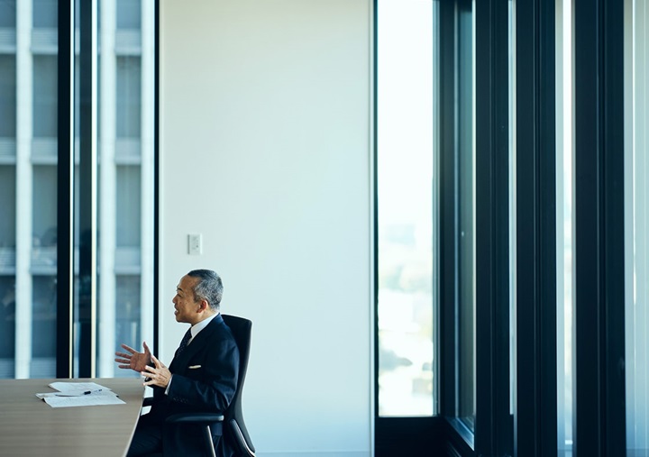 Tomohiro Sudo is sitting on a black chair and speaking.