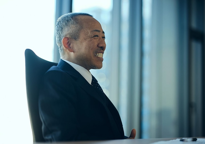 Tomohiro Sudo is sitting on a black chair and speaking.