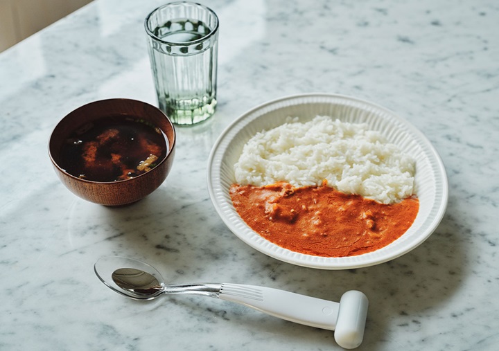 On the right, a large plate of curry rice; on the left, miso soup and a glass of water; in the front, an Electric Salt Spoon.