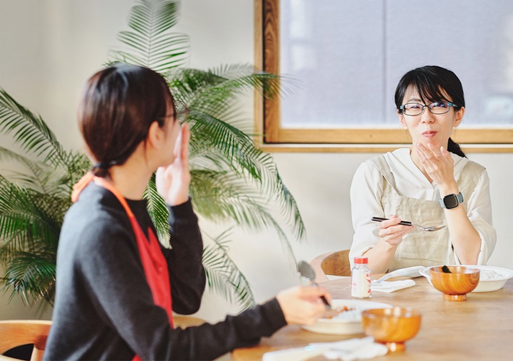 Akari Hasegawa and Ai Sato holding spoons and smiling while talking.